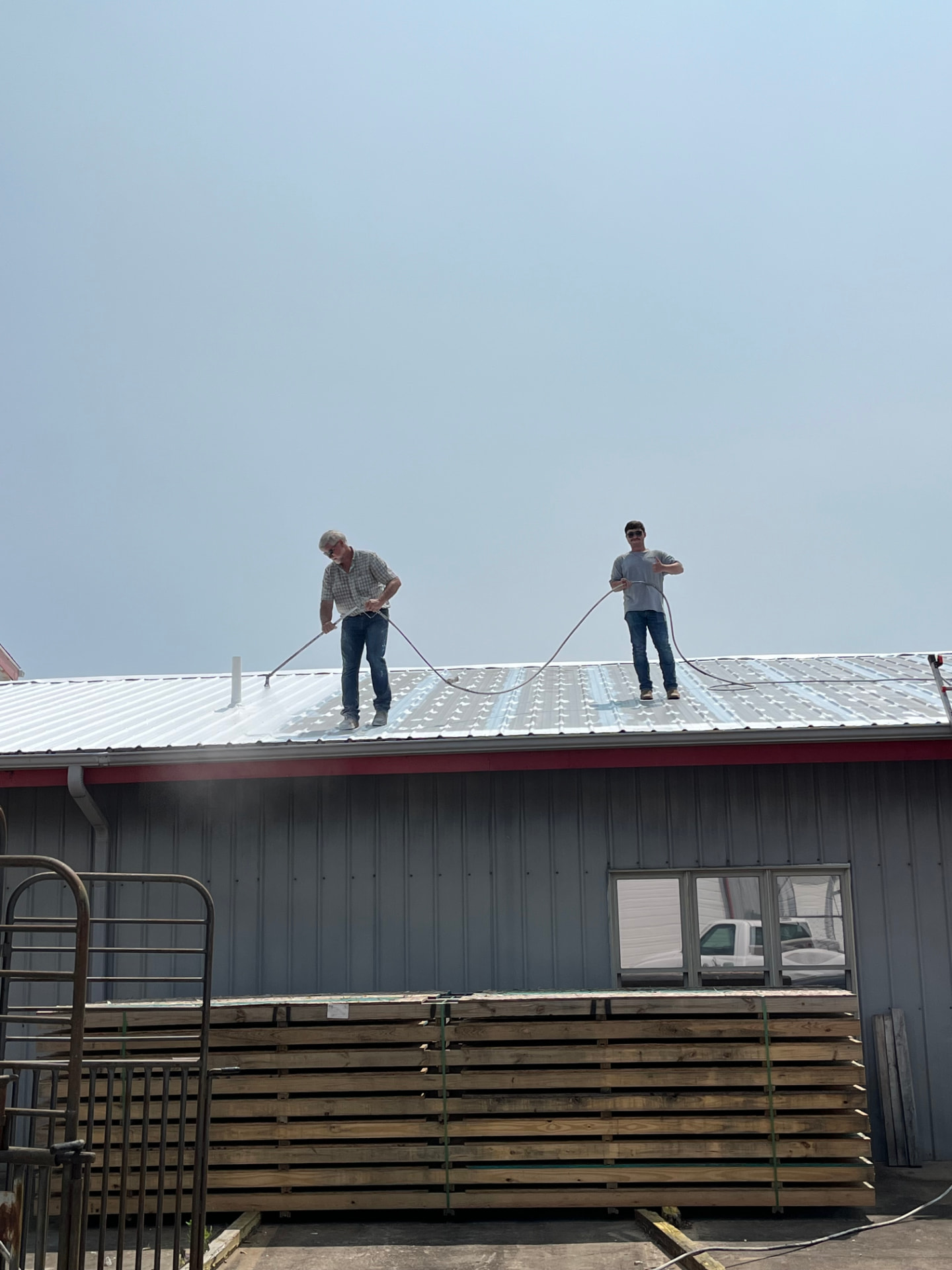 Our crew spray-applying Conklin roof coating on a commercial metal roof